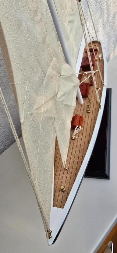 Modell eines Segelboots mit Holzdecks und weißen Segeln.