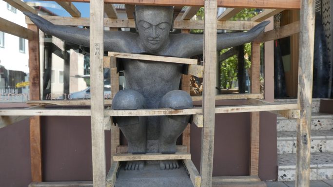 Eine Statue eines sitzenden Mannes, umgeben von Holzrahmen.