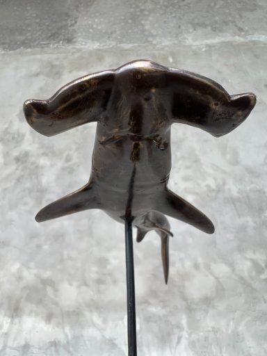 Hammerhai-Statuette aus Metall, von unten betrachtet, auf einem Ständer.