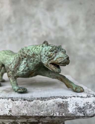 Bronzestatue eines kraftvollen, brüllenden Tigers auf einem Sockel.