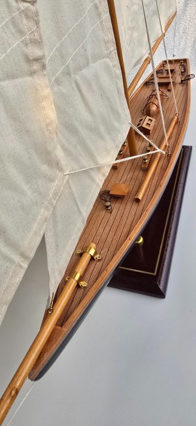 Detailaufnahme eines Schiffsmodells mit bemaltem Rumpf und weißen Segeln.