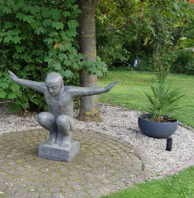 Steinerne Buddha-Statue, aufrecht stehend, Hände in der Rad der Lehrehaltung.