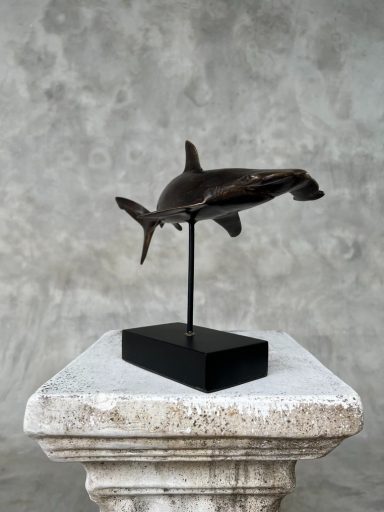 Bronze-Skulptur eines Haifischs auf einem schwarzen Sockel.