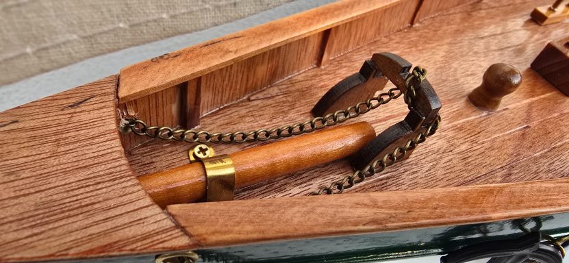 Detail einer antiken Holzbootlenkung mit Kette und Griff.