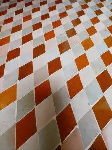 Muster aus rautenförmigen Kacheln in Orange und Weiß auf einem Boden.