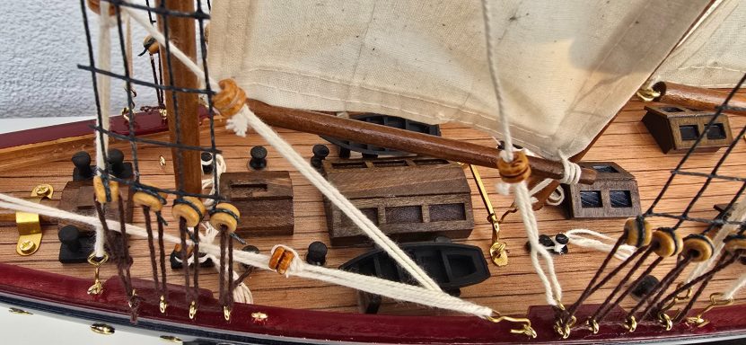 Detailansicht eines Schiffmodells mit Segeln und holzfarbenem Deck.