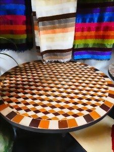 Runde Tischplatte mit geometrischem Muster in Farben Orange, Braun und Beige.