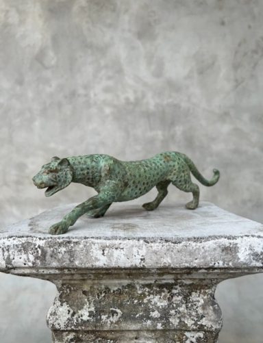 Grüner Bronze-Leopard auf einem grauen Steinuntergrund.