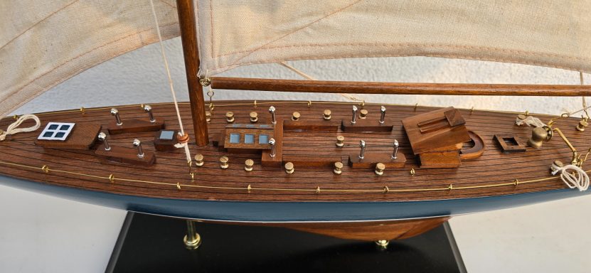 Modell eines Segelbootes mit hölzernem Rumpf und beiger Segelbespannung.