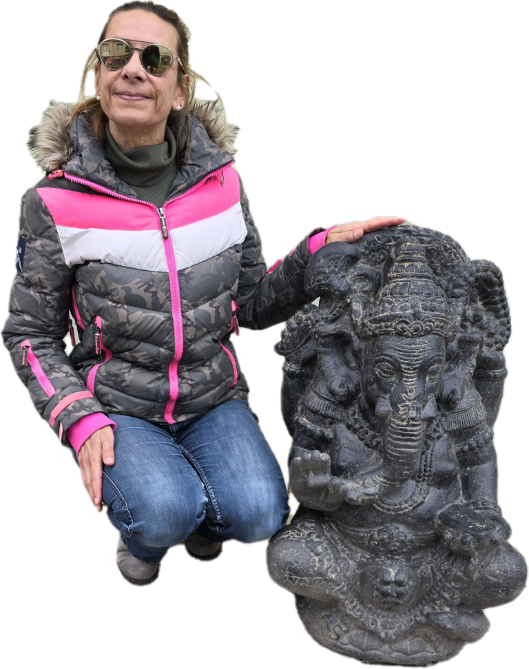 Person in einer Jacke posiert neben einer Statue von Ganesha.