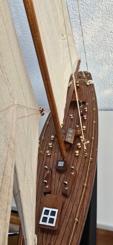 Detailaufnahme eines Holzboots mit Segeln und Steuerbord.