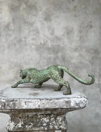 Bronzestatue eines geschmeidigen, sich streckenden Panthers auf einem Steinpodest.