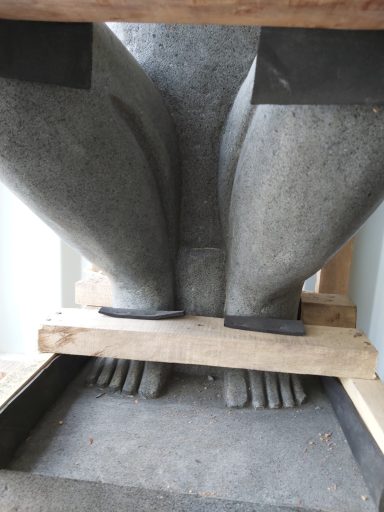Große steinerne Statue mit sichtbar abstehenden Füßen und gestütztem Sockel.