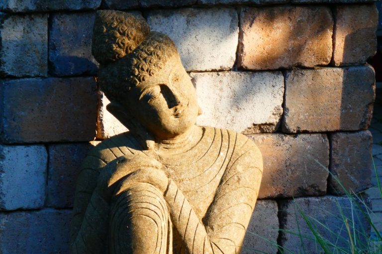 Relaxing Buddha detailreich, umgeben von Steinen im sanften Licht.