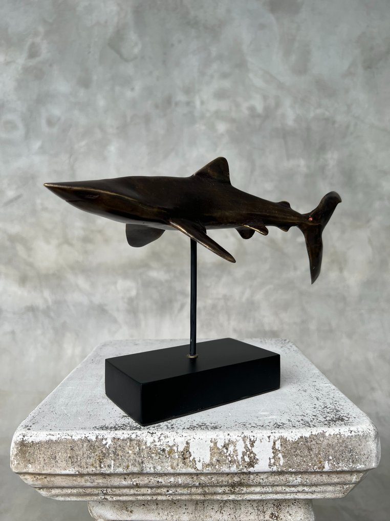Bronzefigur eines Haifischs auf schwarzem Sockel.