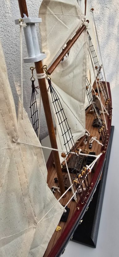 Detailgetreue Schiffsmodell mit weißen Segeln und Holzdetails.