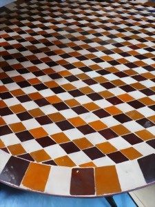 Muster aus karierten, braunen und weißen Fliesen auf einer runden Tischoberfläche.