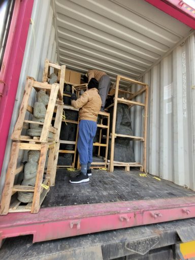 Person in einem Container, der mit Holzregalen arbeitet und Kisten organisiert.