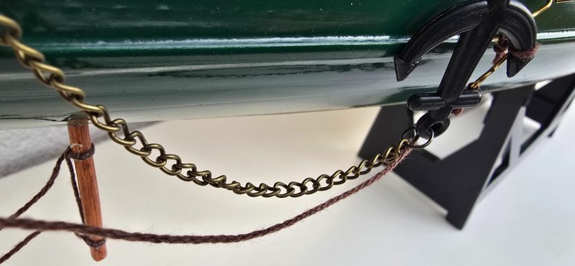 Kette und Anker an einem Boot, mit stabilisierenden Holzstützen.
