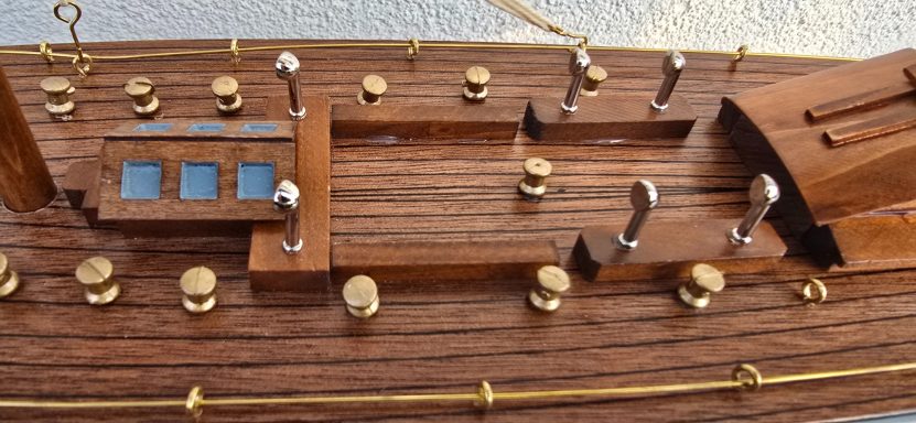 Detailansicht eines Schiffsmodells aus Holz mit Messingbeschlägen und Fenstern.