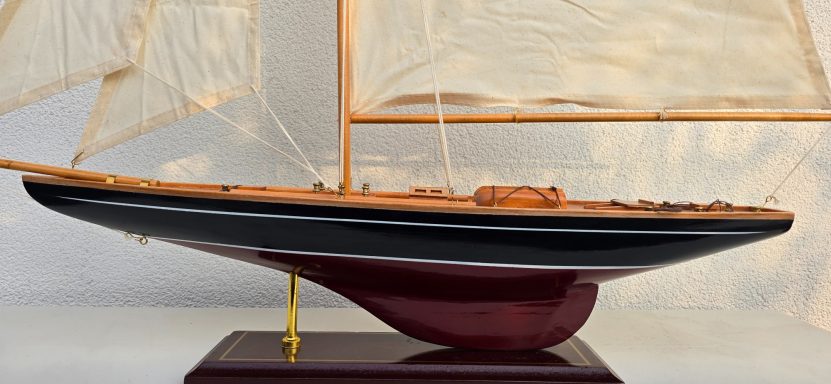 Detailgetreue Modellschiff mit Segeln, präsentierend auf einem Holzsockel.